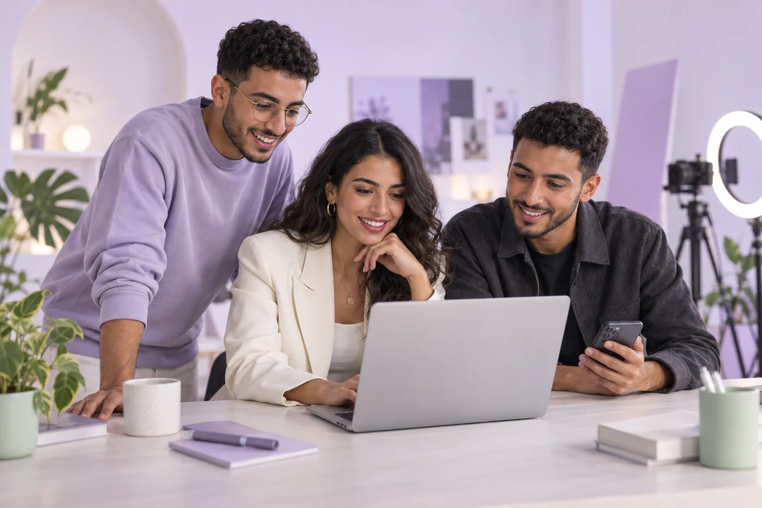 فريق وكالة محتوى يتعاون حول حاسوب في استوديو بألوان اللافندر